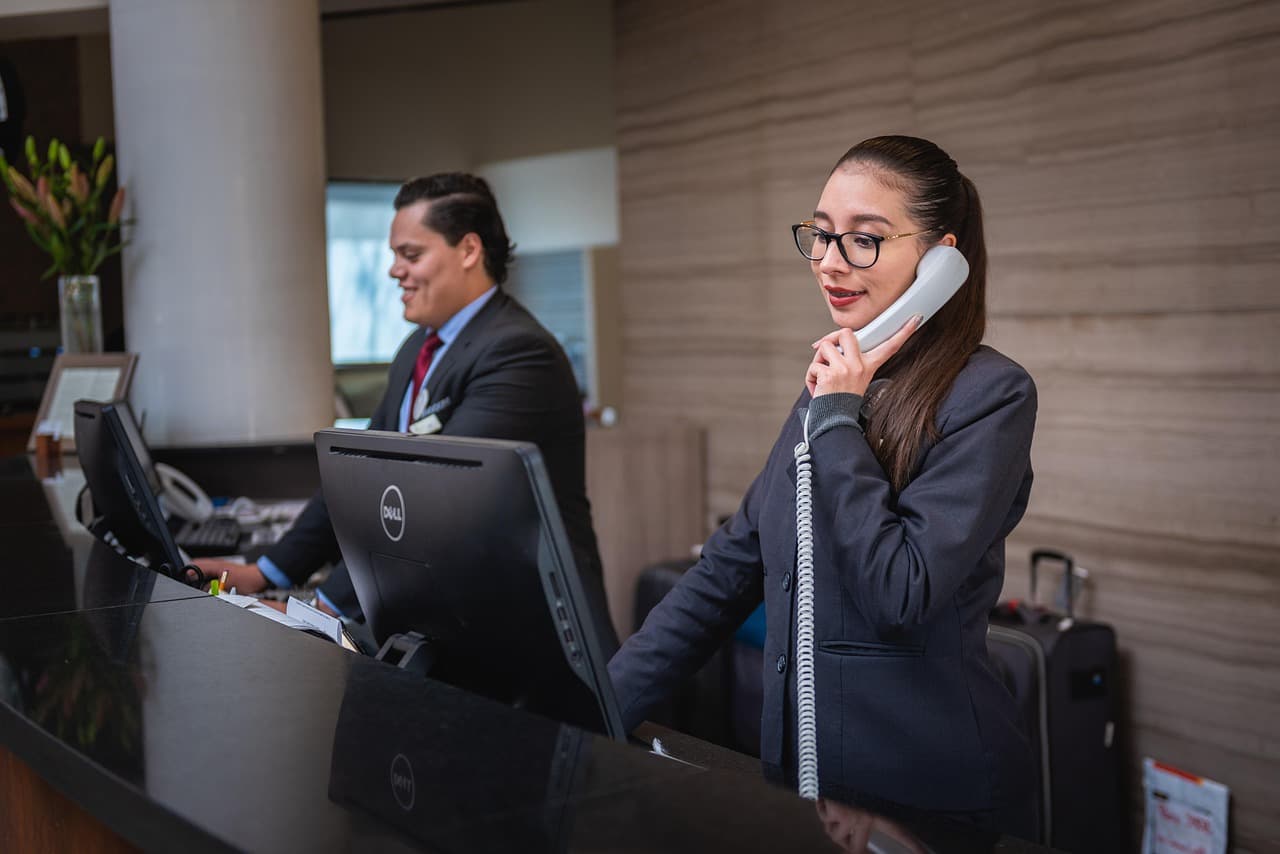 Receptioniste aan de balie van een hotel neemt een telefoontje aan.