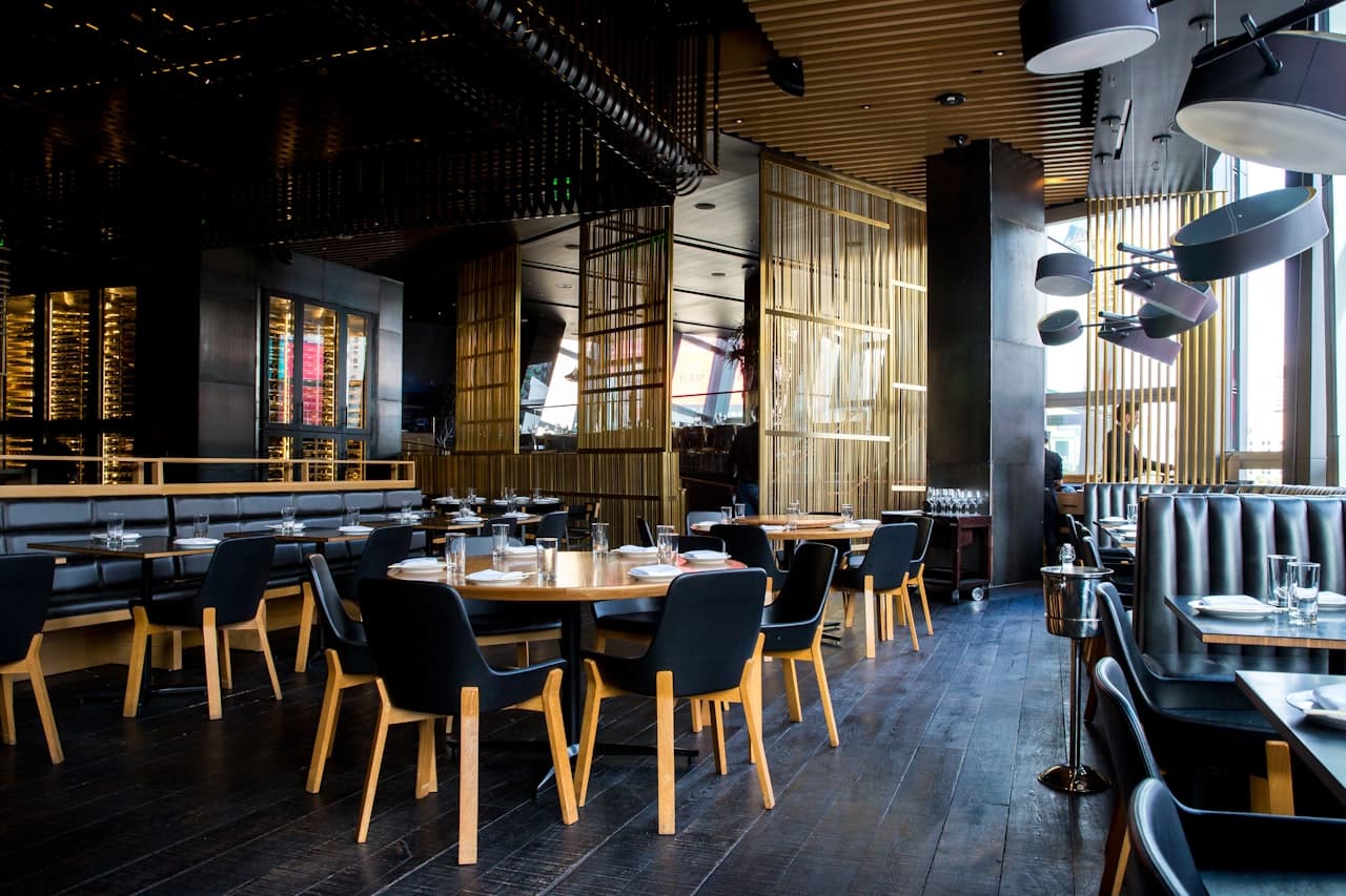 Warm, modern restaurantinterieur met houten tafels en stoelen.
